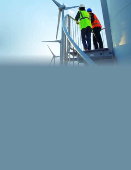 Two people in safety vests looking at windmill