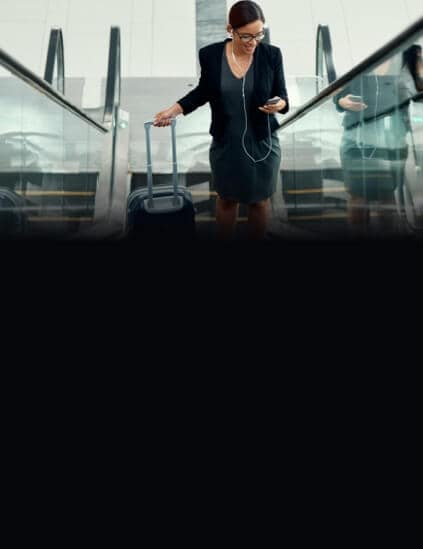 Woman with suitcase on escalator looking at phone