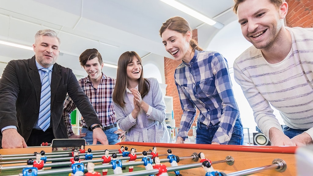 Employees standing around a table football in office