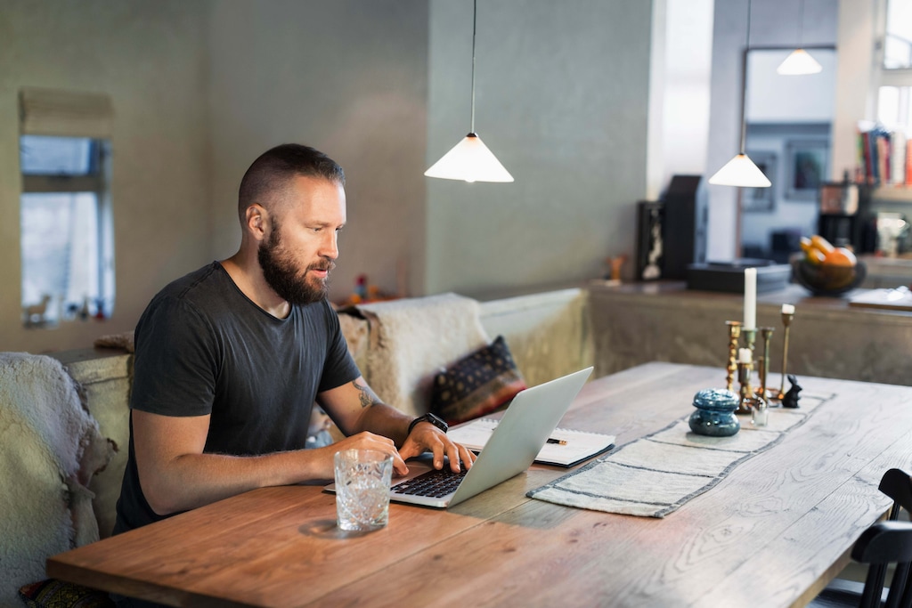 Man working on laptop on dining table in house