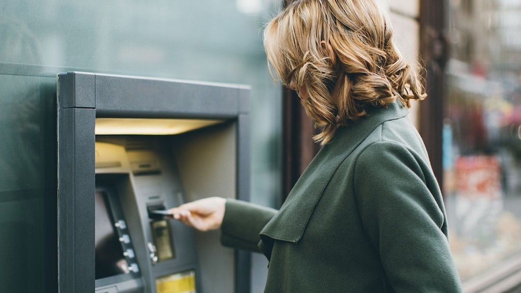 A lady inserting a card in an ATM machine