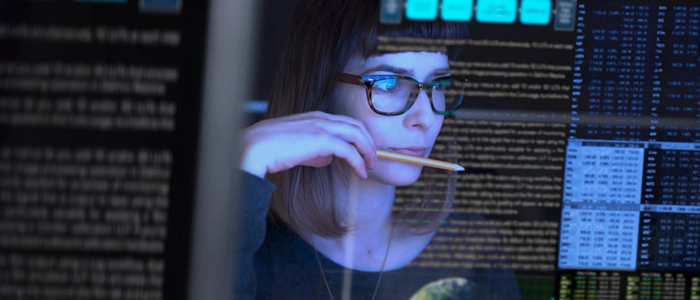 Stock image of a beautiful young woman studying a see through computer screen & contemplating.