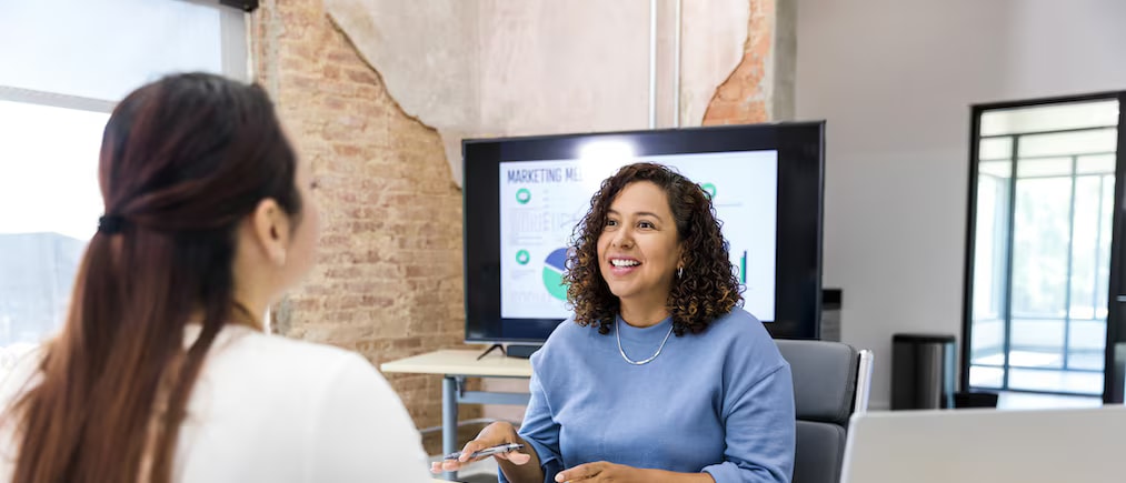 Photo of two women discussing the importance of human resource management in a modern office setting.