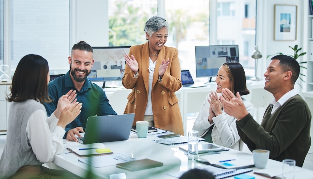 A photo of a marketing team celebrating success in a collaborative office setting, representing a 'pod marketing' structure.