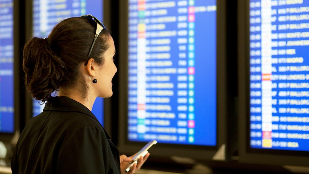 Geschäftsreisender steht am Check-In-Schalter eines Flughafens. 
