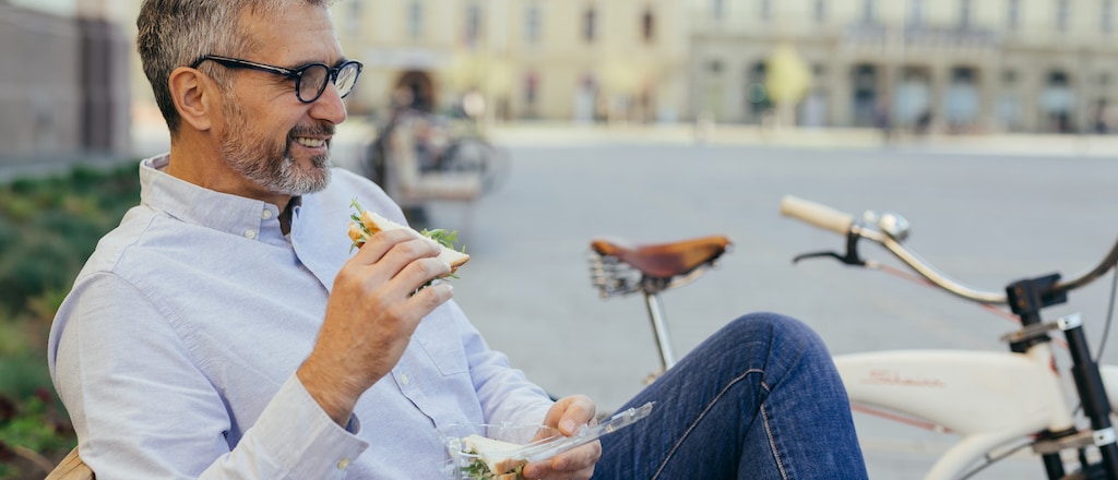 Mann mit Sandwich in der Hand entspannt während seiner Mittagspause.