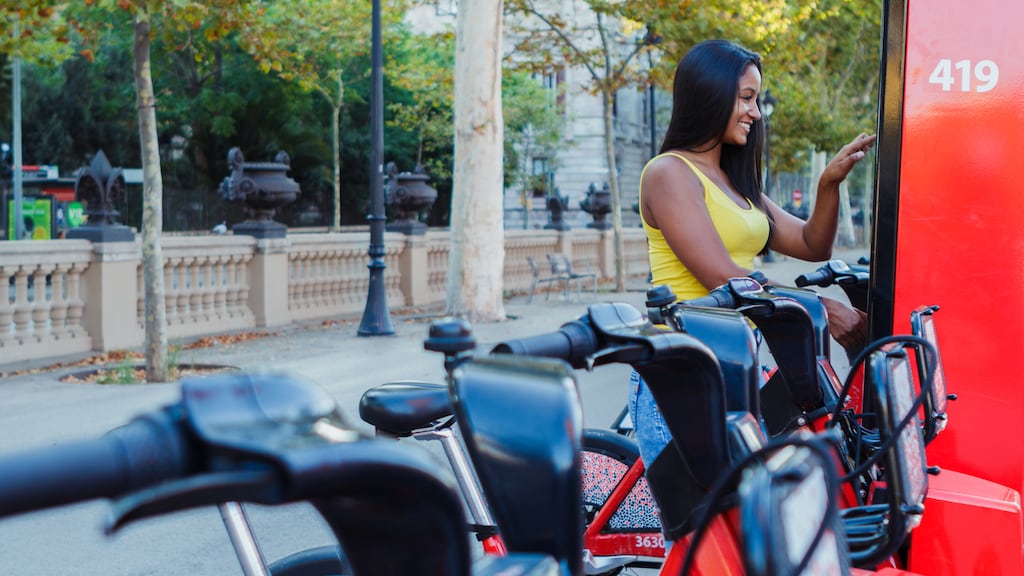 Eine Frau aktiviert ein Fahrrad in einem öffentlichen Fahrradverleih