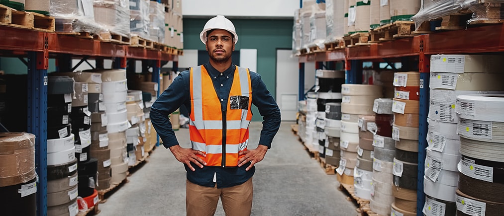 African American Male worker entrepreneur standing in warehouse between shelf filled with goods