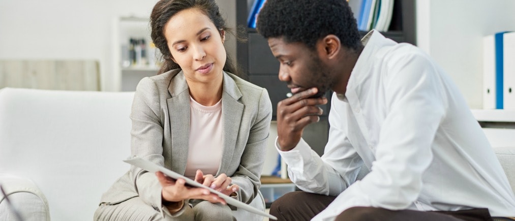 Serious thoughtful multiethnic business partners discussing contract terms and attentively reading agreement in modern office