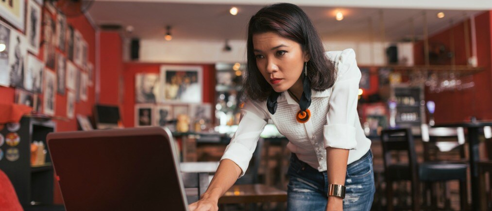 Concerned female bar owner looking at laptop screen