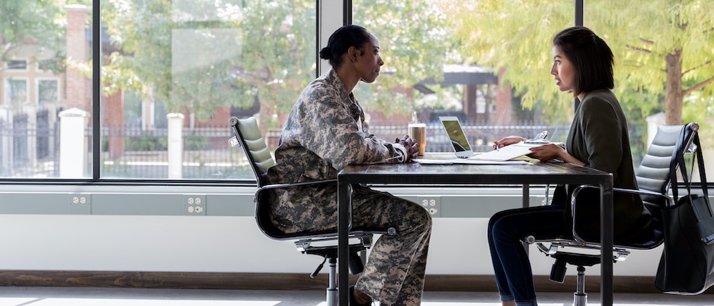 Attentive female soldier meets with a bank manager or loan officer about obtaining a loan.