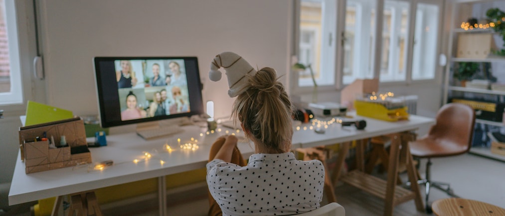 Photo of a young woman celebrating Christmas by having a virtual Christmas party with her friends; celebrating Christmas and holidays apart from friends and family and practicing social distancing.