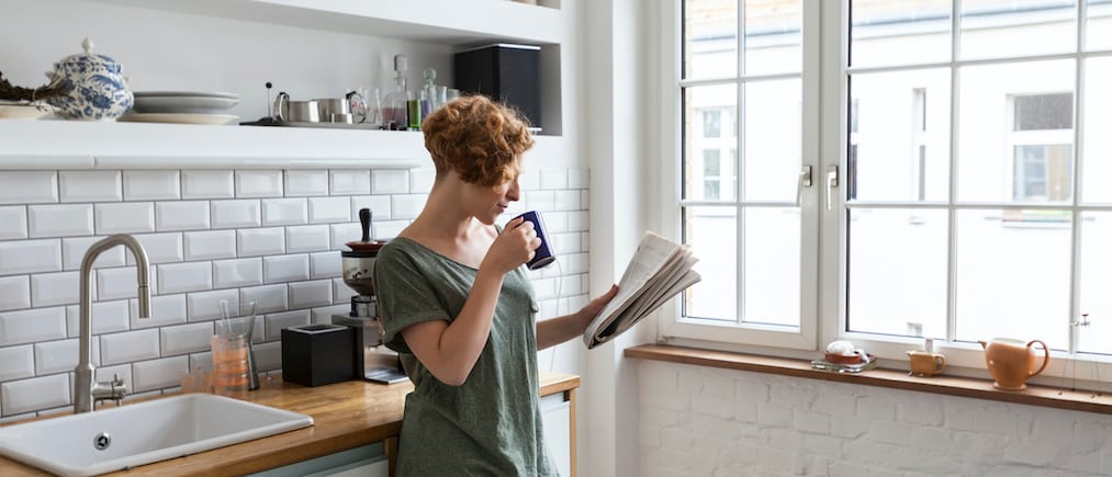 A young women drinks a cup of coffee as she checks her horoscope prediction before she begins her day.