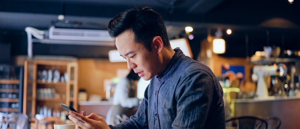 A young professional Taiwanese man working at a table in a small coffee shop in Taipei, Taiwan.