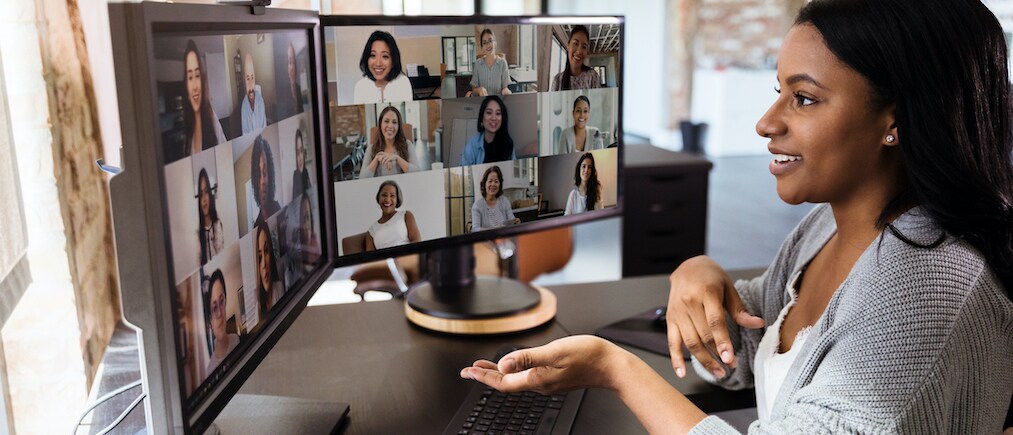 The attractive mid adult woman teleconferences to meet with her diverse colleagues.  She is social distancing due to the coronavirus epidemic.