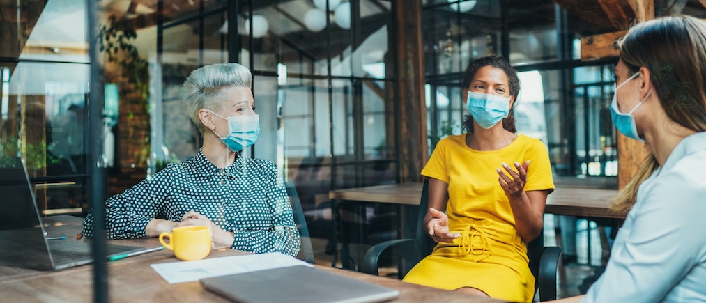 Colleagues - three businesswomen in the office talking while wearing medical face mask during COVID-19