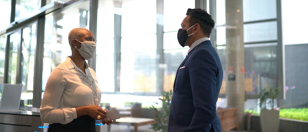 Coworkers talking on office's lobby - with face mask