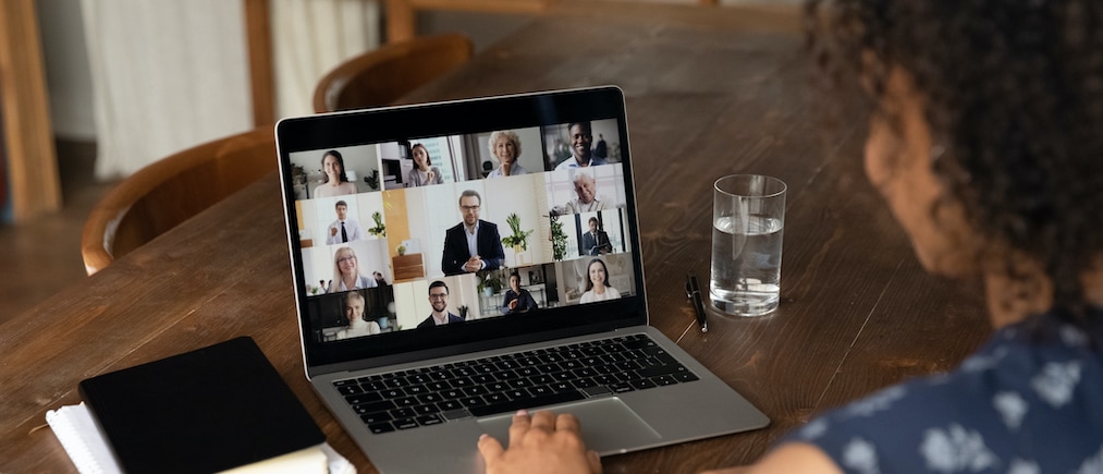 Rear view of female employee talk online video call with diverse multiracial colleagues at home office. Woman worker have webcam digital virtual conference or web meeting with businesspeople.