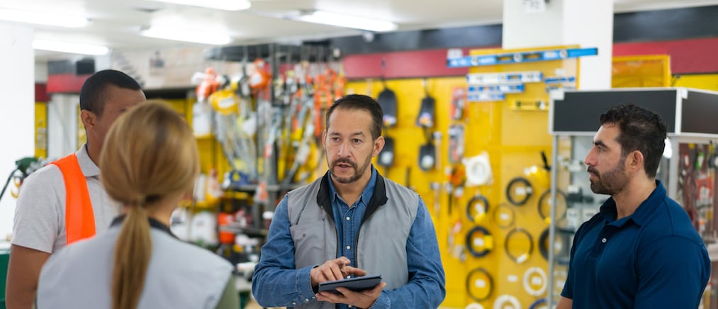 Latin American Store manager talking to a group of employees at a hardware store - personnel training concepts 
