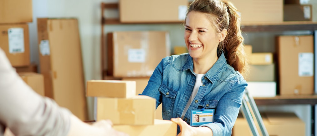 Delivery business. happy young female in jeans in the warehouse giving parcel.