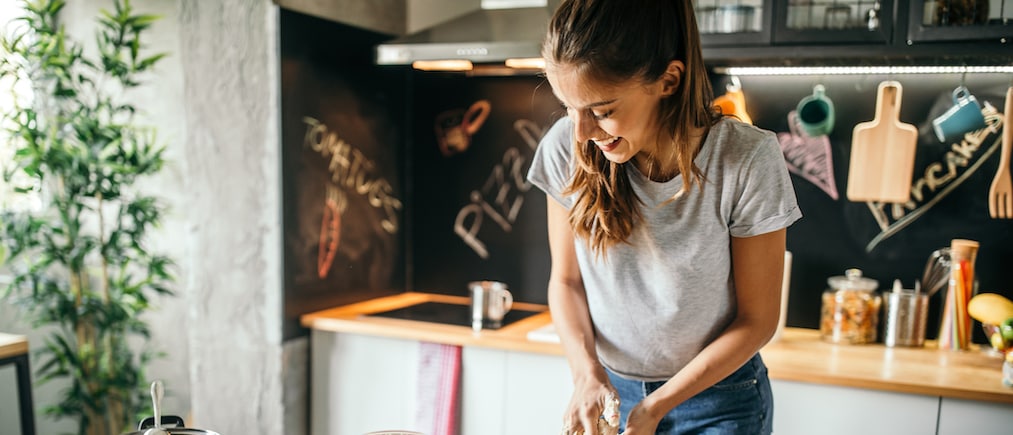 Photo of young woman preparing pizza at home