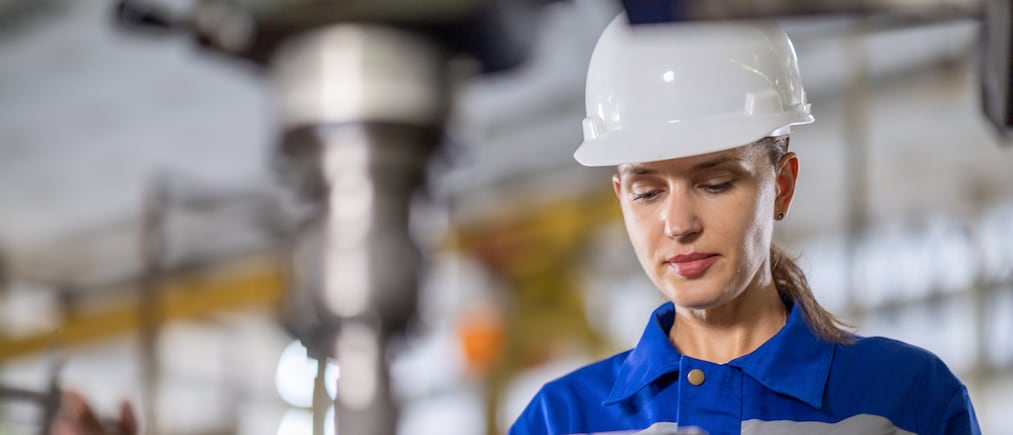 Caucasian White Female Engineer controls the quality using a tablet device to inspect the drilling machine in the factory.
