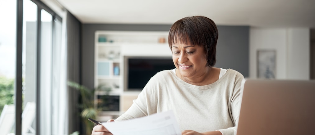 Cropped shot of a happy senior woman sitting alone in her living room and going through paperwork