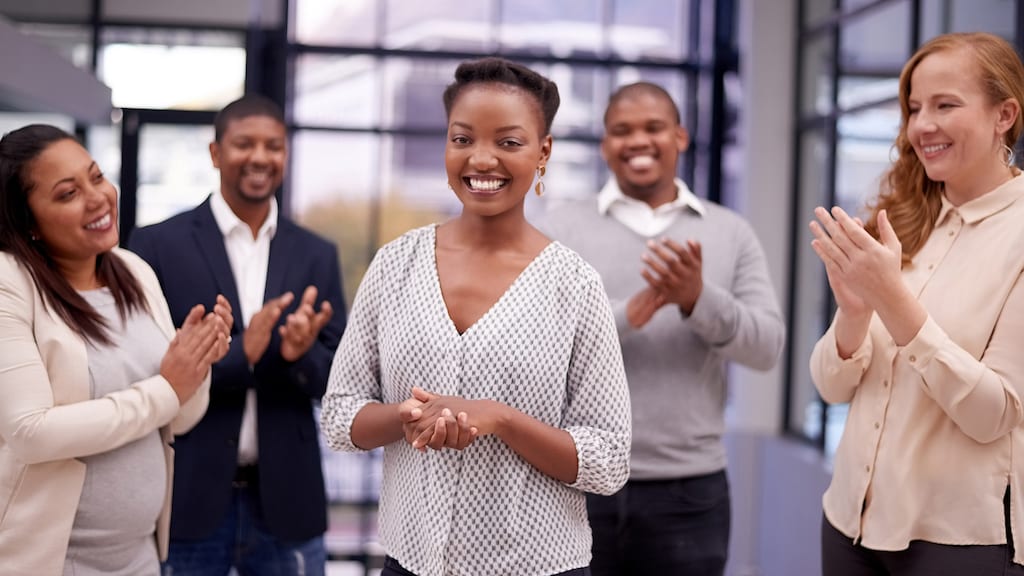 Shot of a young businesswoman being applauded by her colleagues in a modern office