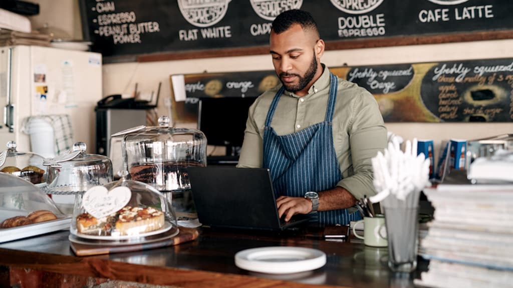 Shot of a young man using a laptop while working in a cafe