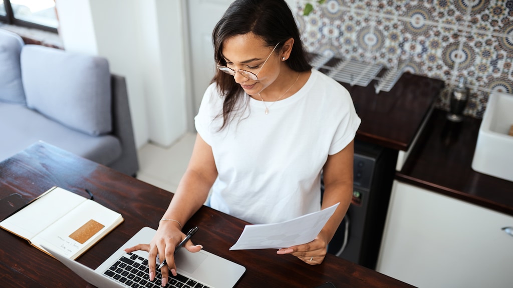 Shot of a young woman going through paperwork while working from home