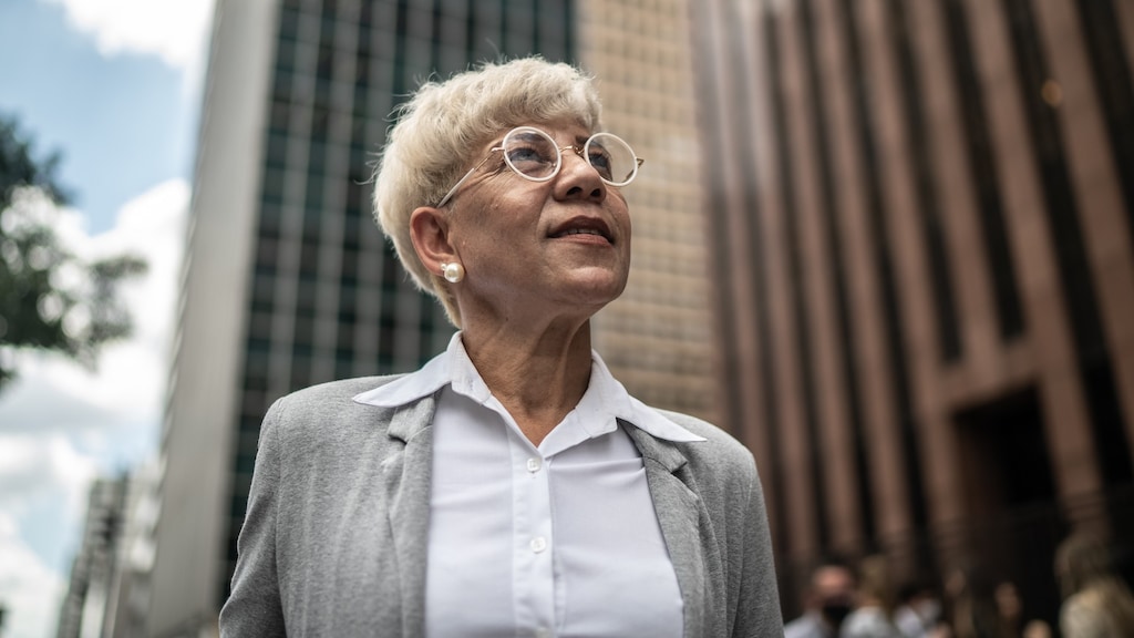 A mature businesswoman stands outside looking inspired