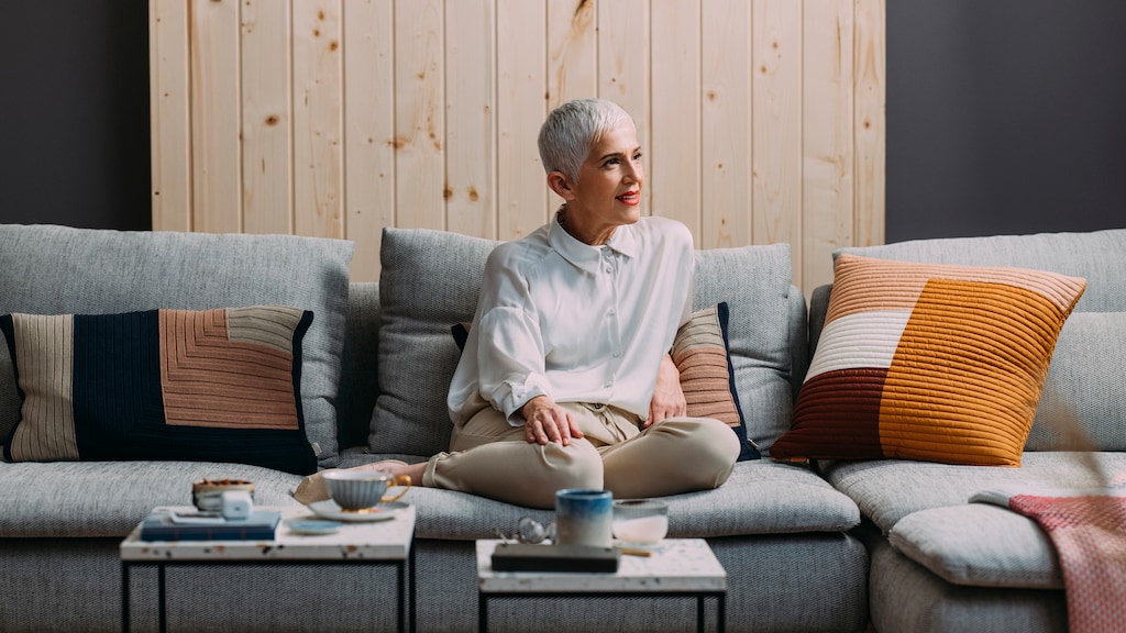 Senior woman with a pixie haircut enjoying a slow afternoon, sitting in her living room and drinking tea