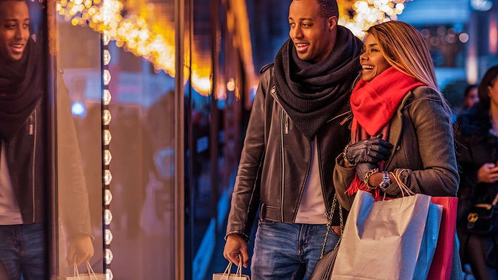 Beautiful black male and female couple enjoying winter shopping in the high street