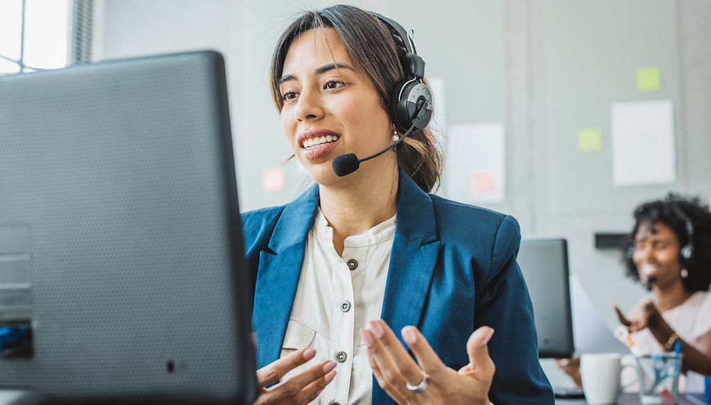 Friendly woman in call center service talking with costumers by headset. Call center and diverse people group in business.