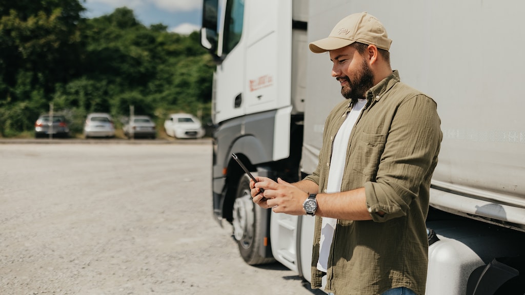 Mid adult man wearing hat using technology in front of the big truck