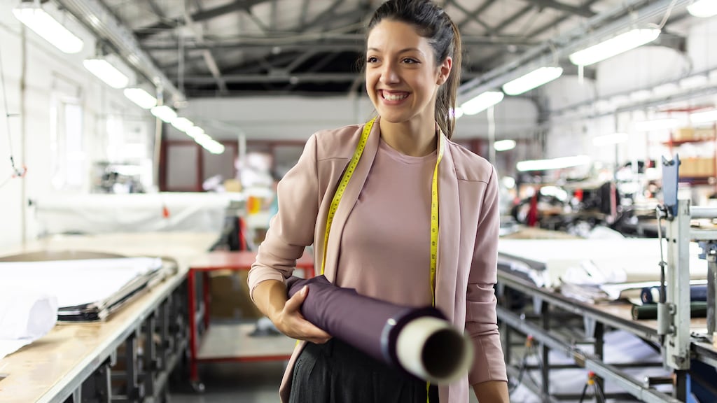 Smiling young woman working in a fashion factory