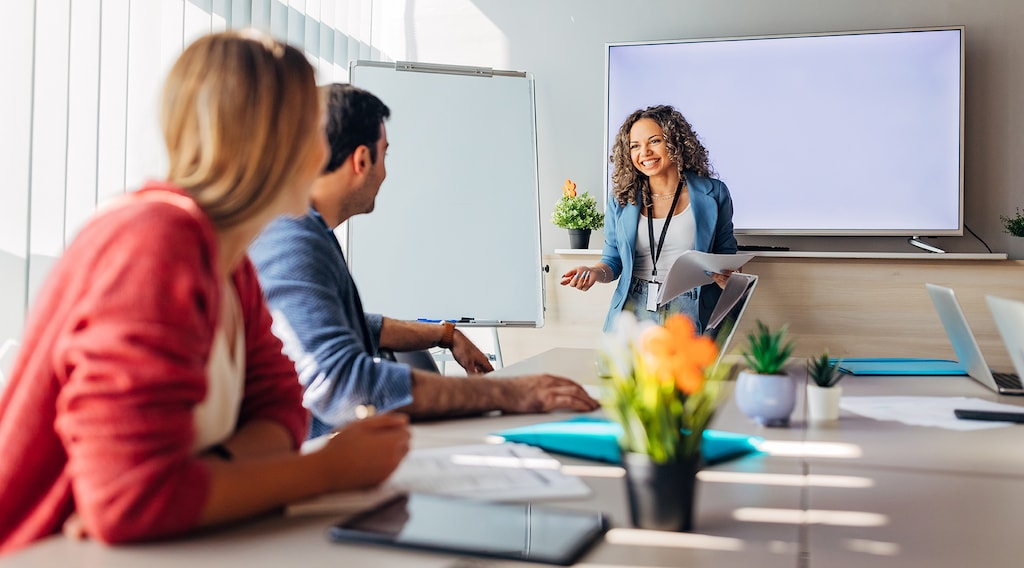 Smiling Hispanic team leader holding meeting in conference room with her business colleagues