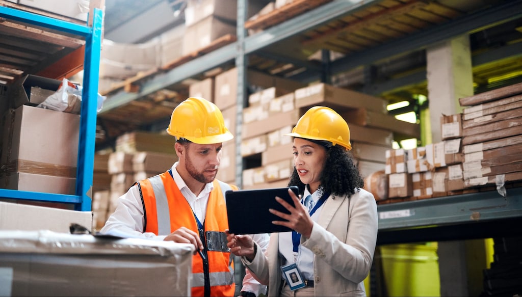 Warehouse manager showing employee a tablet