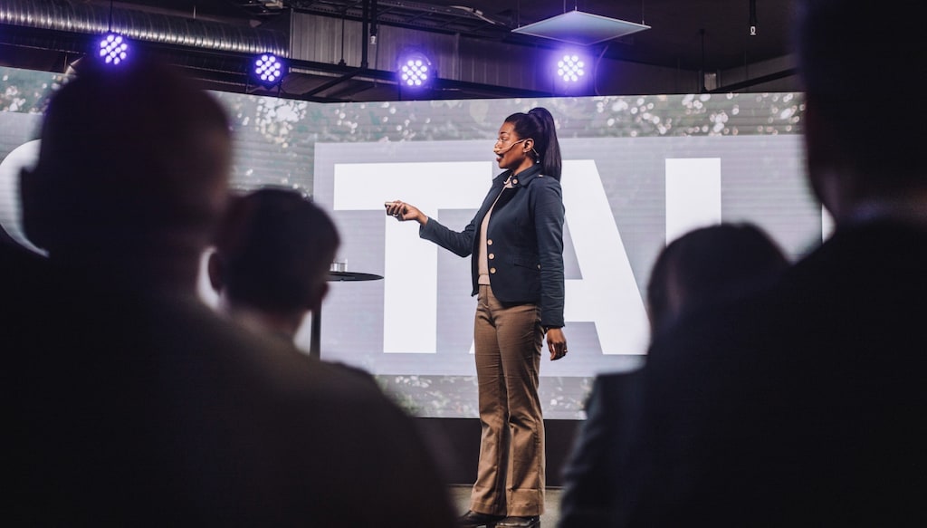 woman on stage giving a talk to a crowd