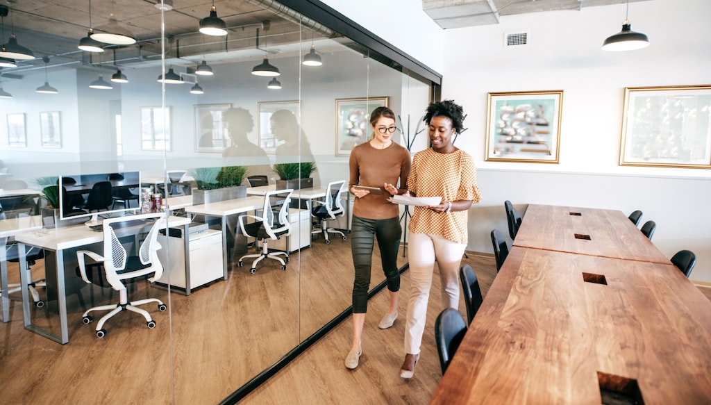 Colleagues leaving a meeting room while discussing a project