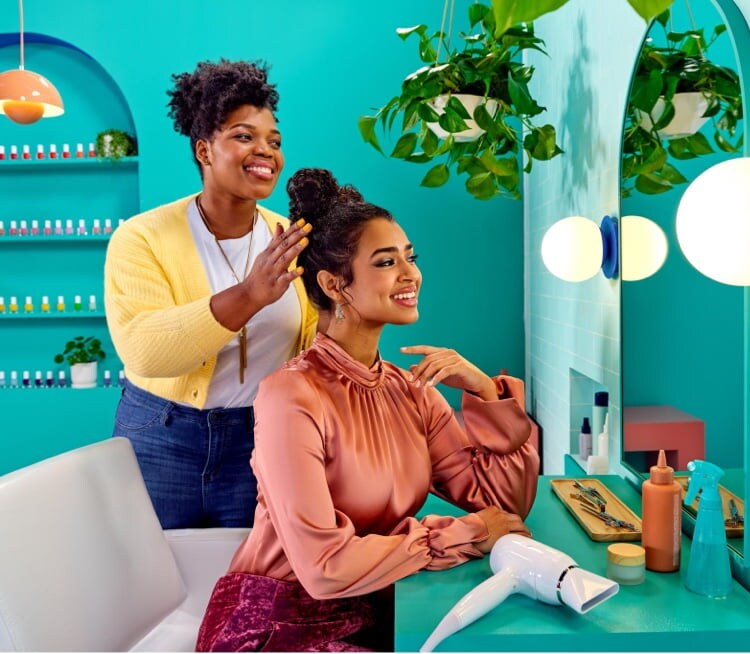 Hairstylist fixing a woman's hair up-do at a salon, woman is checking her hair out in mirror